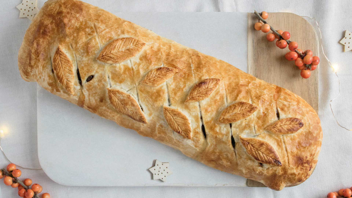 Ansicht von oben eines gefüllten Blätterteigs mit aufgesetzten Blättern aus Blätterteig, als Dekoration weiße Weihnachtsterne mit kleinen Löchern