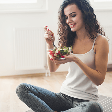 Eine junge Frau isst einen bunten Salat