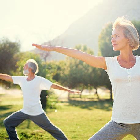 Ein Mann und eine Frau mittleren Alters machen Yoga im Park