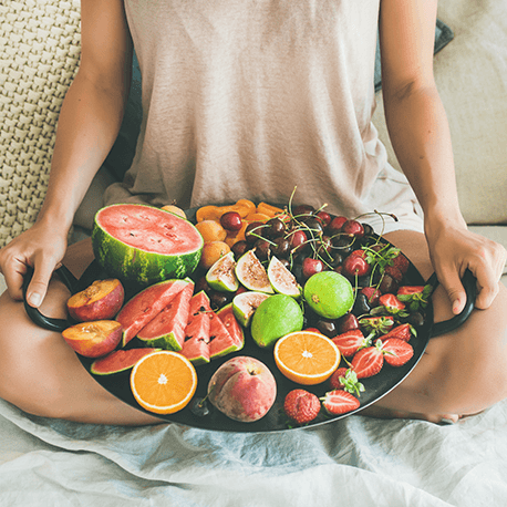 Eine Frau hält ein Riesenpfanne mit frischem Obst in der Hand